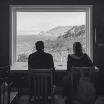 Schwarz-Weiß-Foto von zwei Personen vor Fenster